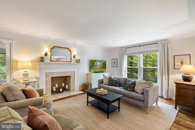  - living area featuring light wood-type flooring, a fireplace with flush hearth, and ornamental molding