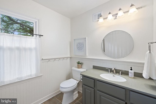  - bathroom with vanity, toilet, tile patterned flooring, and wainscoting