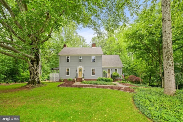  - colonial inspired home featuring a chimney and a front yard