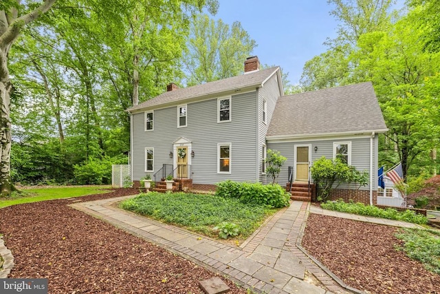  - colonial home featuring a chimney and roof with shingles