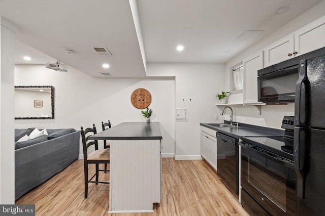  - kitchen with black appliances, dark countertops, a sink, a kitchen breakfast bar, and white cabinets
