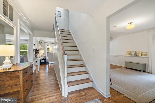  - stairs featuring wood finished floors, ornamental molding, and baseboards
