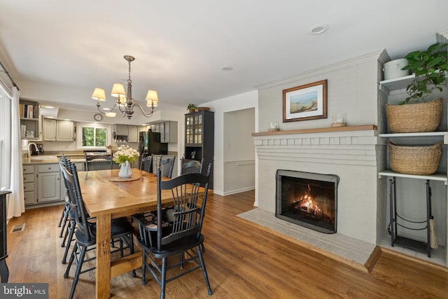  - dining room with a chandelier, a brick fireplace, and light wood-type flooring