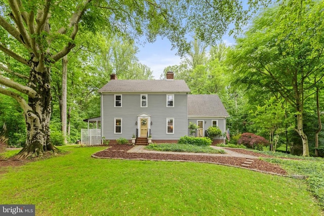 - colonial home with a chimney and a front yard