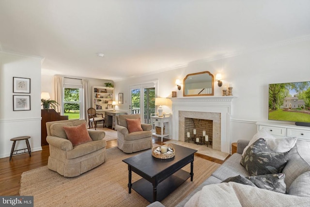  - living area with crown molding, wood finished floors, and a fireplace