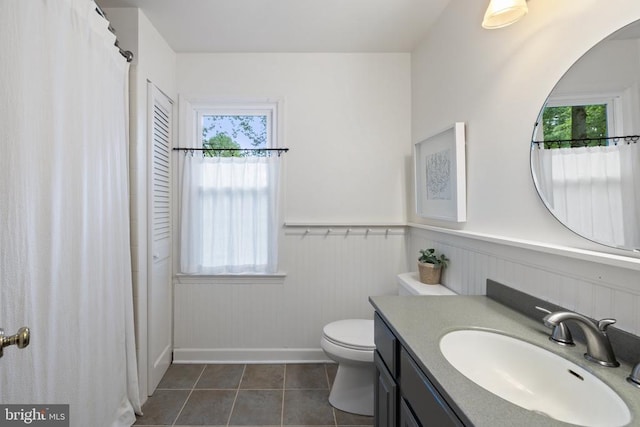  - full bathroom featuring vanity, plenty of natural light, toilet, wainscoting, and tile patterned floors