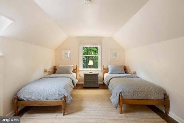  - bedroom featuring vaulted ceiling, baseboards, and wood finished floors