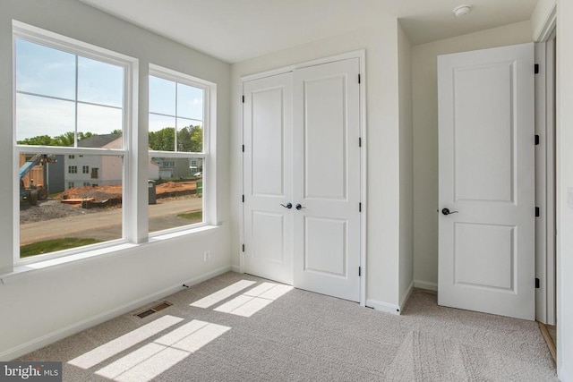 unfurnished bedroom featuring baseboards, a closet, visible vents, and carpet