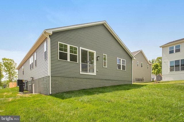 rear view of property with central AC and a lawn