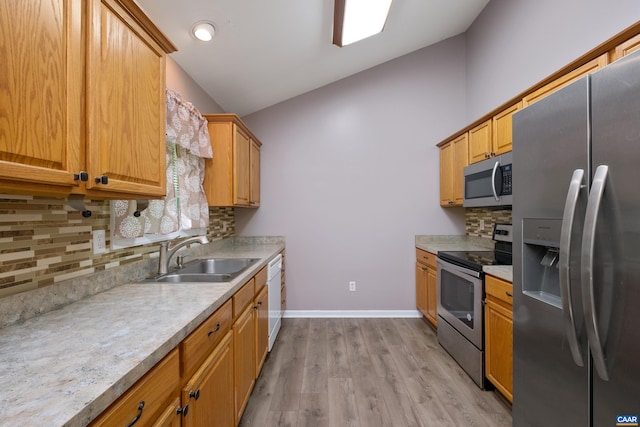 kitchen featuring stainless steel appliances, a sink, vaulted ceiling, backsplash, and light countertops