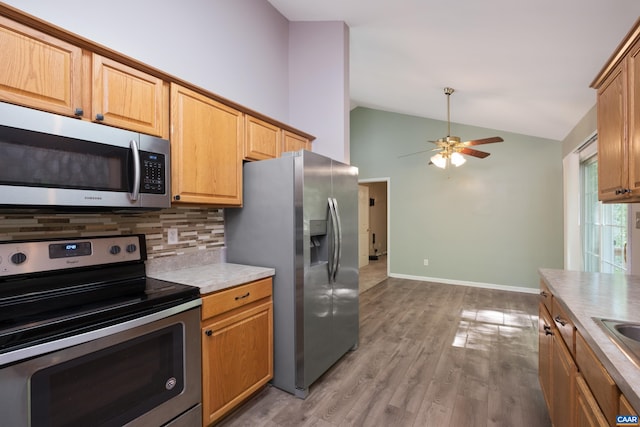kitchen featuring stainless steel appliances, lofted ceiling, backsplash, ceiling fan, and light countertops