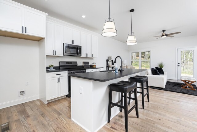 kitchen featuring a kitchen island with sink, sink, white cabinetry, and stainless steel appliances