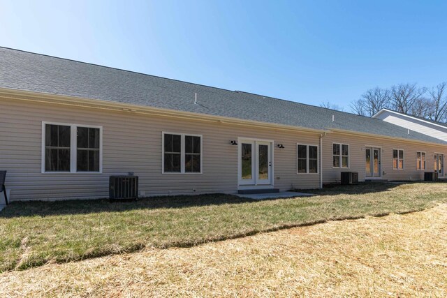 rear view of house featuring central AC and a lawn