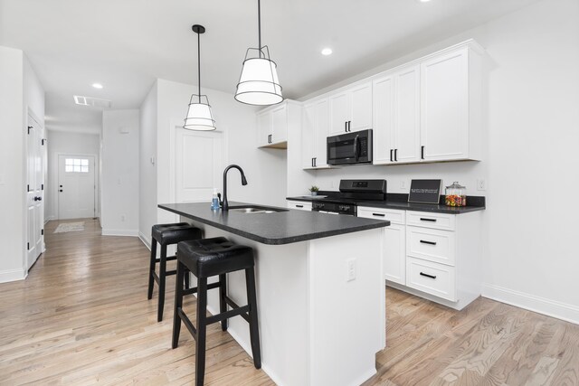 kitchen featuring pendant lighting, white cabinetry, an island with sink, sink, and black range with electric stovetop