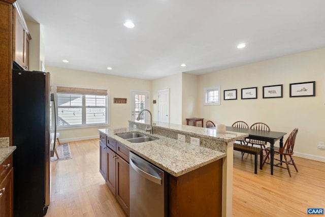 kitchen featuring light wood-style flooring, a sink, stainless steel appliances, baseboards, and recessed lighting