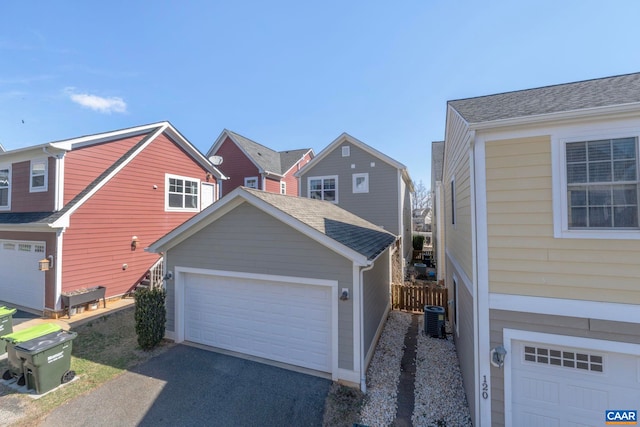 view of front facade featuring a garage, central AC unit, and fence