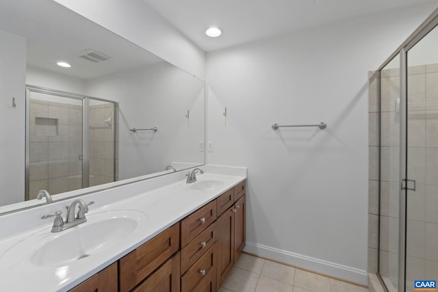 bathroom featuring a shower stall, tile patterned flooring, double vanity, and baseboards