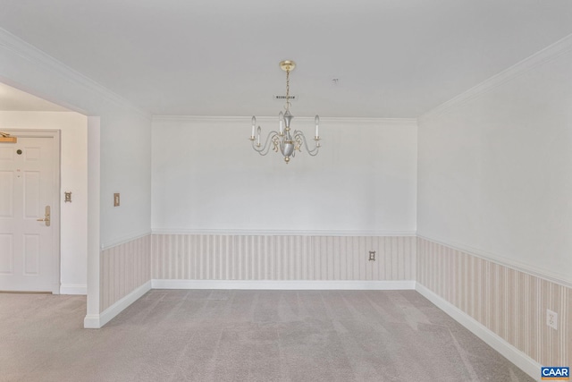 unfurnished room with an inviting chandelier, ornamental molding, and carpet floors