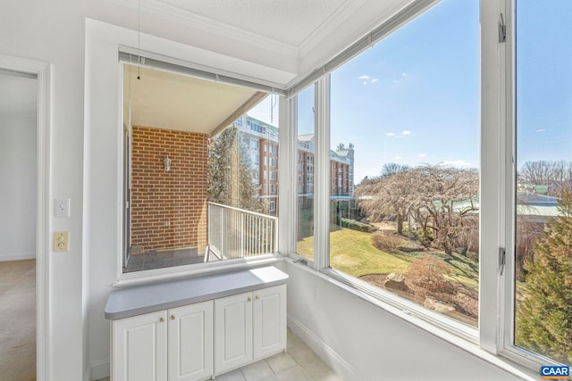 unfurnished sunroom featuring crown molding, baseboards, and tile patterned flooring