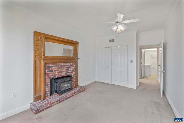 unfurnished living room with carpet, ornamental molding, ceiling fan, visible vents, and a wood stove