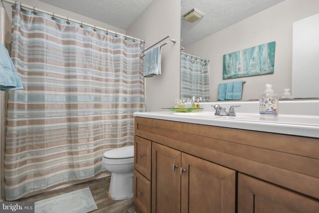 740 Lakeview Pkwy, Locust Grove, VA 22508 - bathroom with wood finished floors, a textured ceiling, toilet, vanity, and a shower with shower curtain