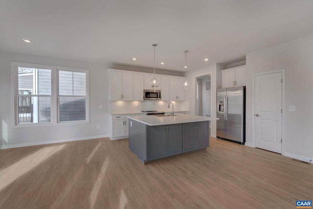 3053 Rambling Brook Ln, Crozet, VA 22932 - kitchen with stainless steel appliances, light wood-type flooring, a center island with sink, white cabinets, and recessed lighting