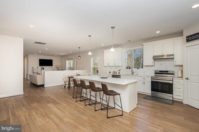 208 Yorktown Blvd, Locust Grove, VA 22508 - kitchen with electric stove, under cabinet range hood, tasteful backsplash, light countertops, and a kitchen breakfast bar