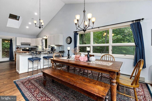 living area featuring a textured ceiling, vaulted ceiling with skylight, a stone fireplace, and wood finished floors