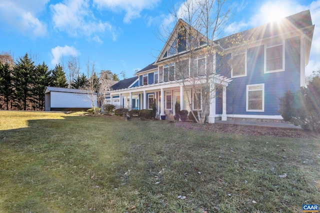 rear view of property with covered porch, a yard, and metal roof