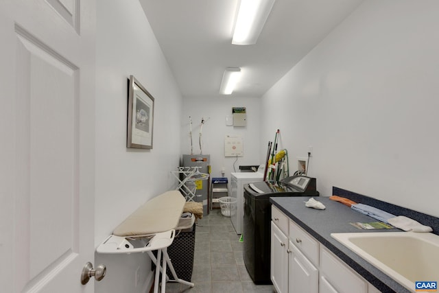 laundry area featuring washing machine and dryer, light tile patterned flooring, a sink, water heater, and cabinet space