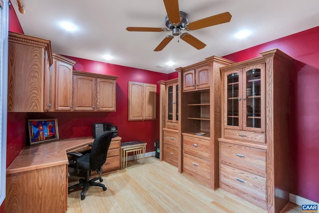 office space featuring baseboards, light wood-style floors, ceiling fan, and built in study area