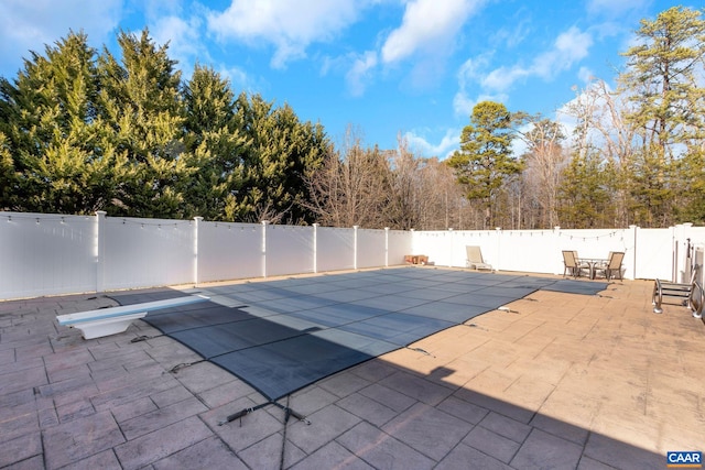 view of swimming pool featuring a patio area, a fenced in pool, a fenced backyard, and a diving board
