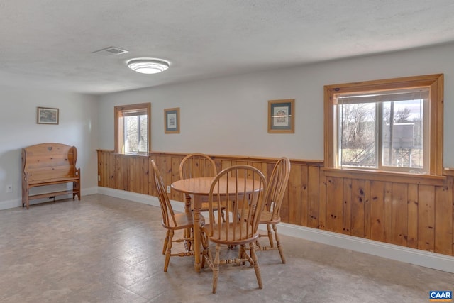 3340 James River Rd, Howardsville, VA 24562 - dining space featuring a wainscoted wall, a textured ceiling, wood walls, and visible vents