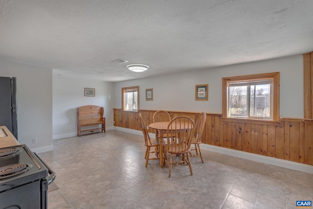 3340 James River Rd, Howardsville, VA 24562 - dining space with a wainscoted wall, wood walls, and a textured ceiling