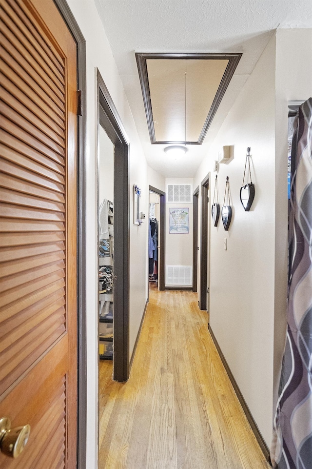 corridor featuring attic access and light wood-style floors