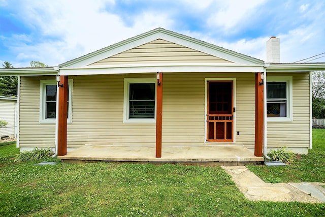 view of front of property featuring a front yard, a porch, and a chimney
