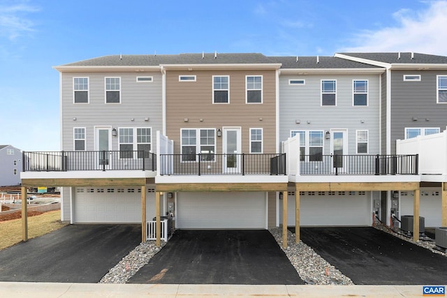 rear view of property featuring driveway, cooling unit, and a garage