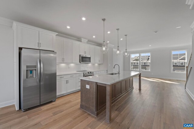 kitchen with a sink, baseboards, an island with sink, and appliances with stainless steel finishes