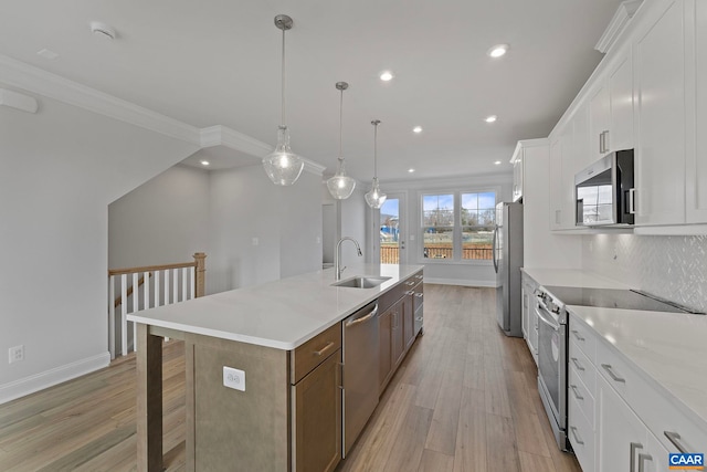kitchen featuring a sink, light wood finished floors, a spacious island, and appliances with stainless steel finishes