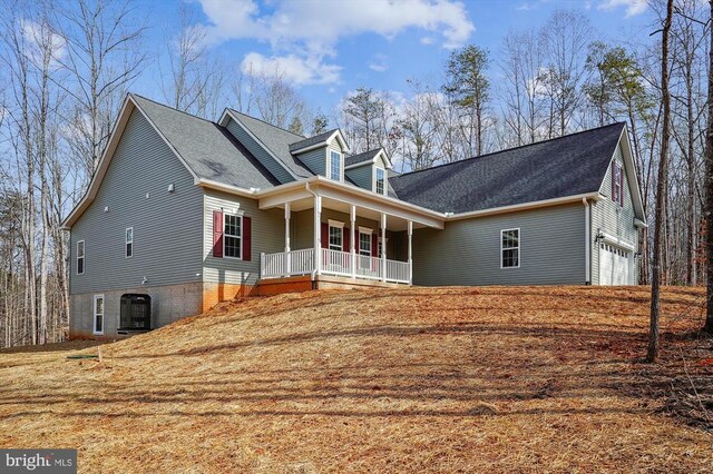  - rear view of house featuring a porch, an attached garage, and a shingled roof