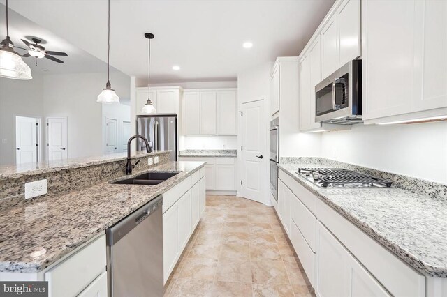  - kitchen with stainless steel appliances, a sink, white cabinets, a ceiling fan, and decorative light fixtures