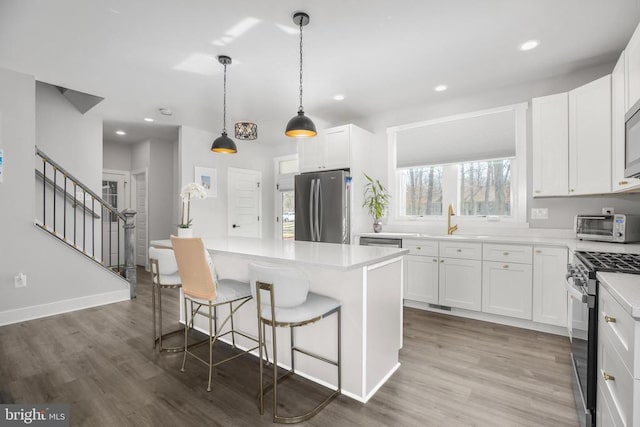105 Chesterfield Ct, Locust Grove, VA 22508 - kitchen featuring appliances with stainless steel finishes, wood finished floors, a kitchen island, a breakfast bar, and white cabinets