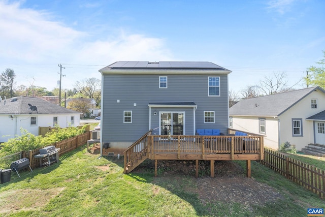 back of house featuring a wooden deck and roof mounted solar panels