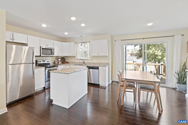 kitchen featuring stainless steel appliances, a sink, white cabinetry, a center island, and recessed lighting