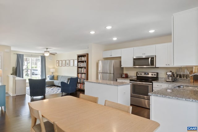 kitchen featuring stainless steel appliances, a sink, white cabinetry, a center island, and recessed lighting