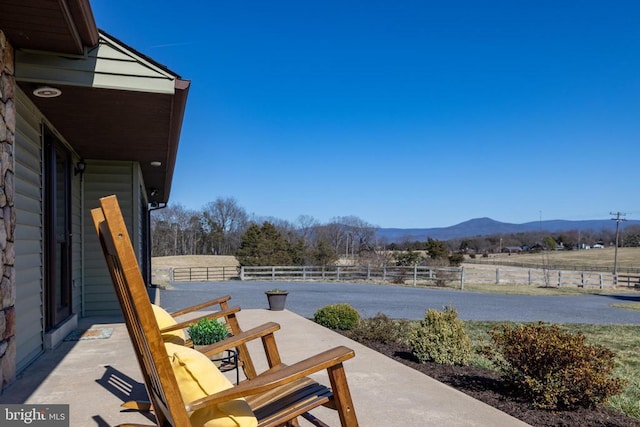 view of patio with a mountain view, fence, and a view of rural / pastoral area