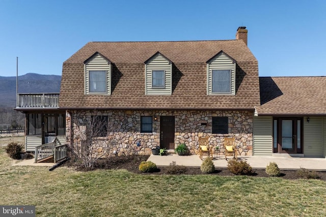view of front of house featuring stone siding, a shingled roof, and a front lawn