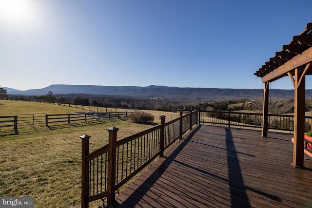 deck with a rural view, a mountain view, and a lawn
