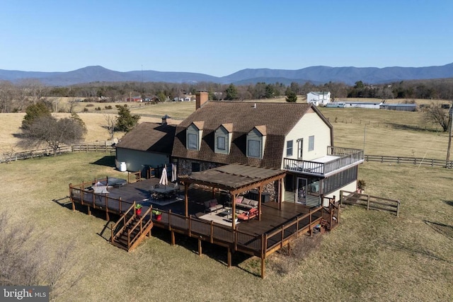 rear view of house featuring a deck with mountain view, a chimney, fence, and a view of rural / pastoral area