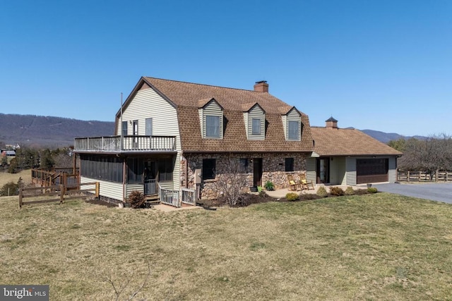 colonial inspired home featuring a chimney, driveway, an attached garage, a mountain view, and stone siding